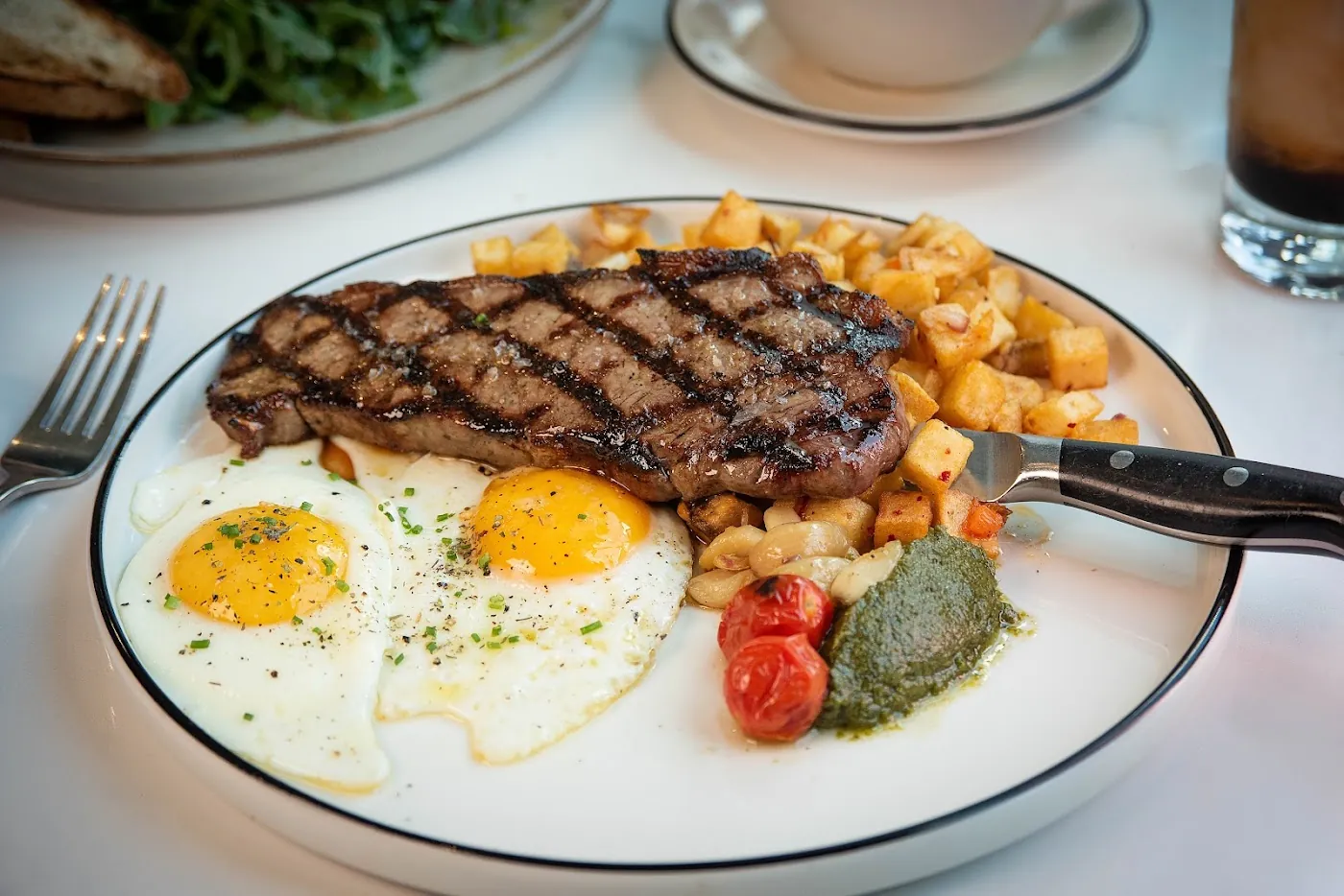 Steak and sunny-side-up eggs with golden potatoes at The Great Commoner